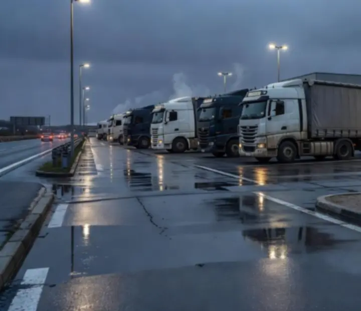 Station-service européenne en soirée, camions alignés sous un ciel bleu nuit